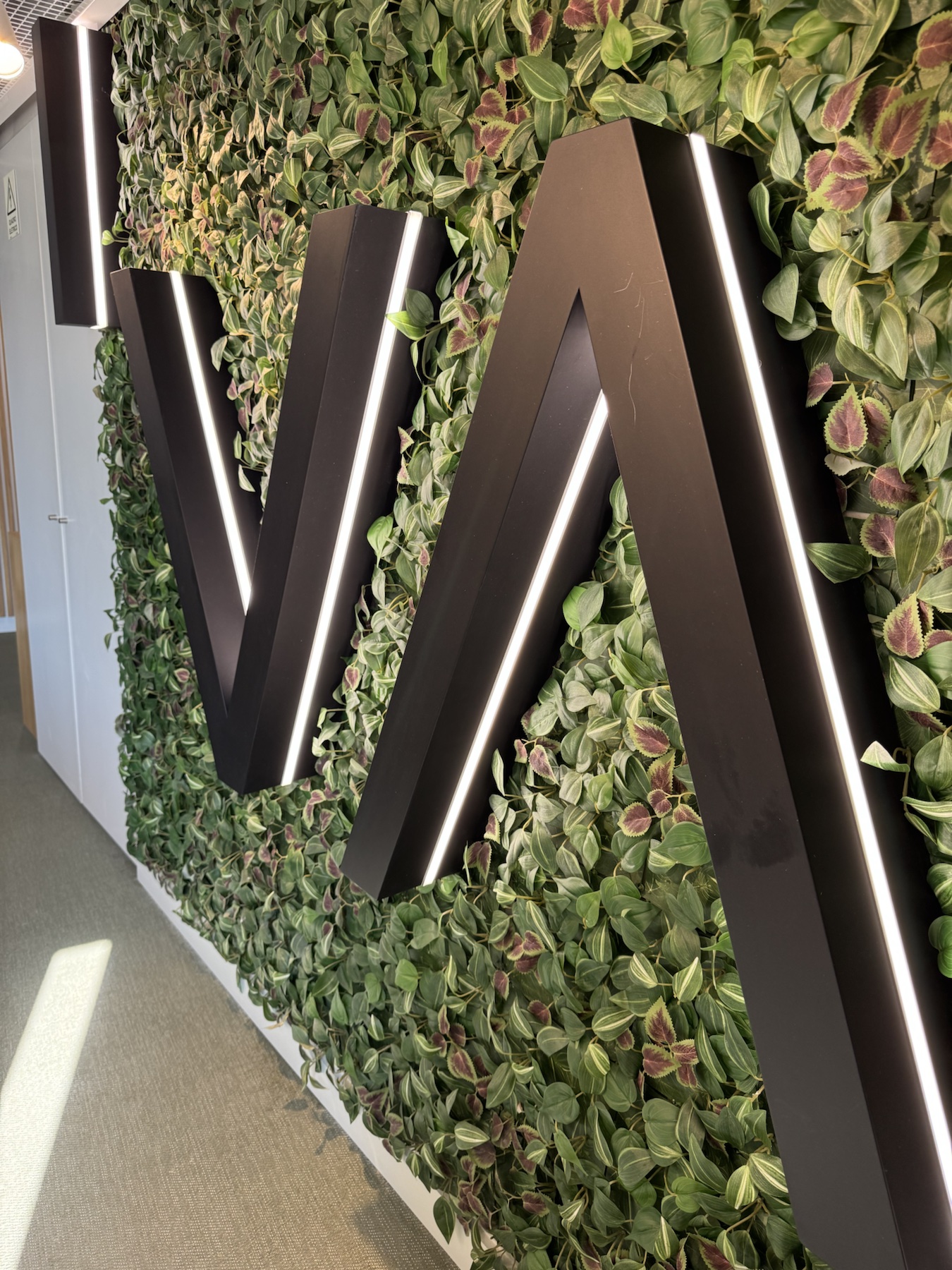 Begrünte Wand mit Vertical-Schriftzug im Coworking-Space in Porto.