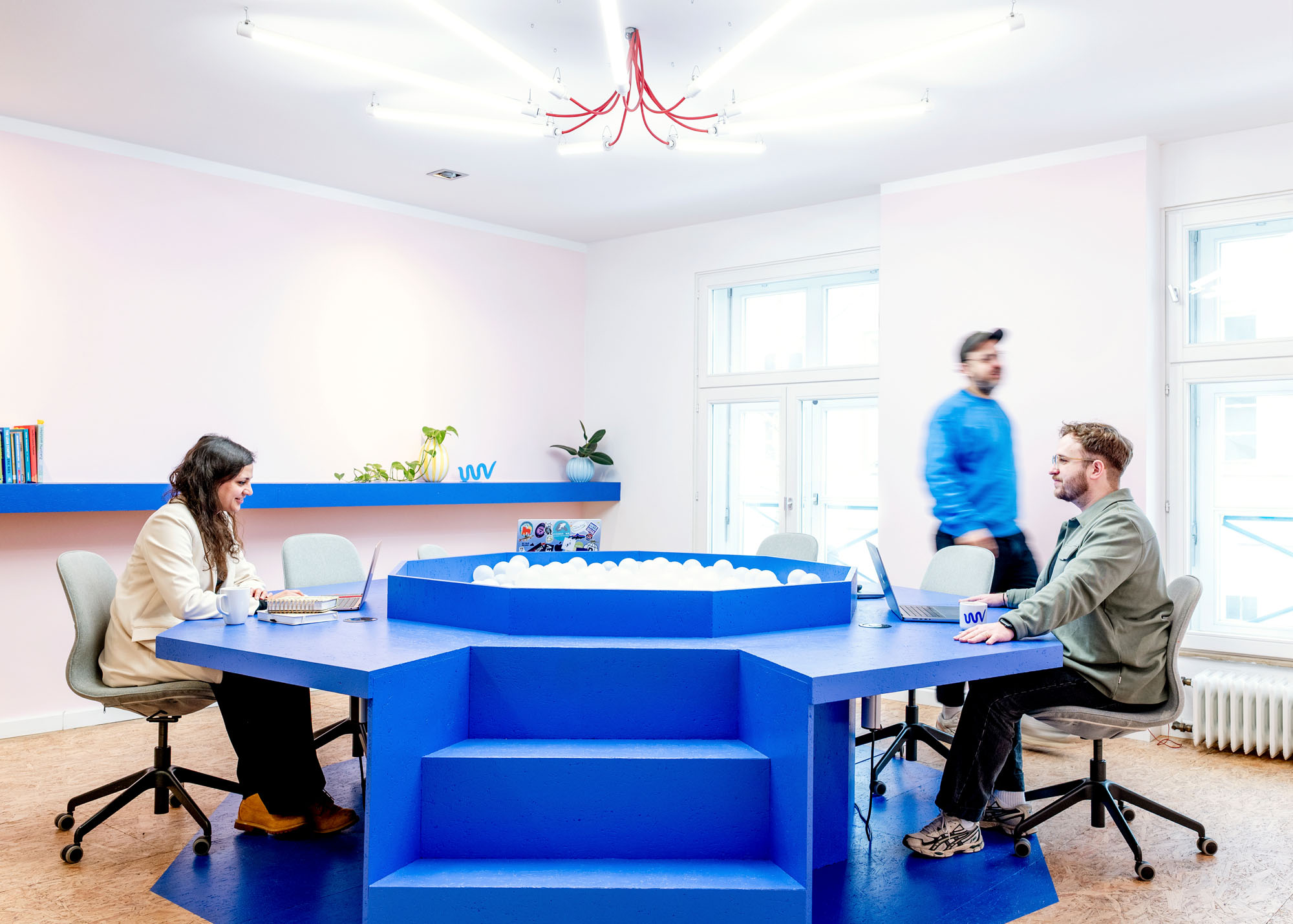 Blauer Bällebad-Arbeitstisch im Coworking-Space WEIT.VORN in Kassel mit arbeitenden Personen.